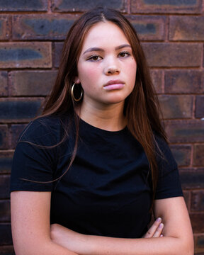 moody teen headshot against brick wall