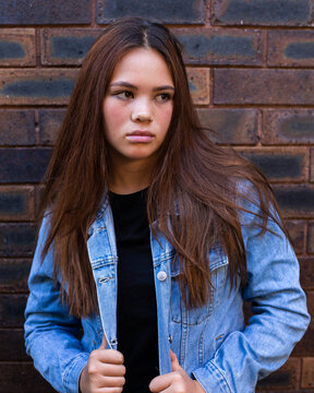 mixed race girl with long brown hair and denim jacket
