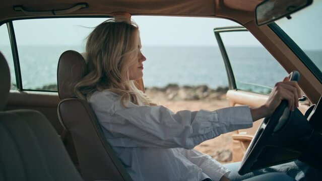 Worried woman sitting automobile at ocean shore close up. Blonde beating wheel 