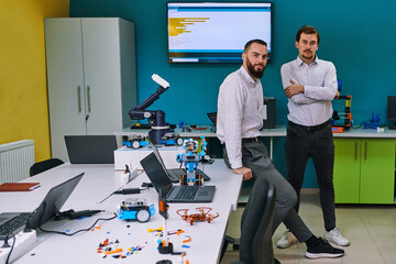 A group of colleagues collaborate in a lab while testing a 3D printer, demonstrating their...
