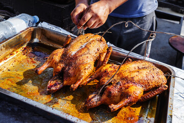 Cooking duck meat on fire and coals. The chef inspects a roasted bird on a metal tray. Close-up. unrecognizable person