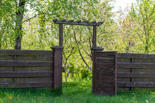 Wooden garden fence with open door and green grass on a spring day