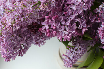 Bouquet of blooming lilac in a vase on the windowsill by the window