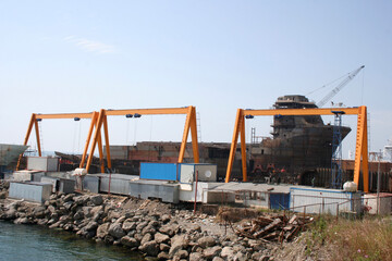 Fototapeta premium Shipbuilding pier and crane. Workers working on the pier.