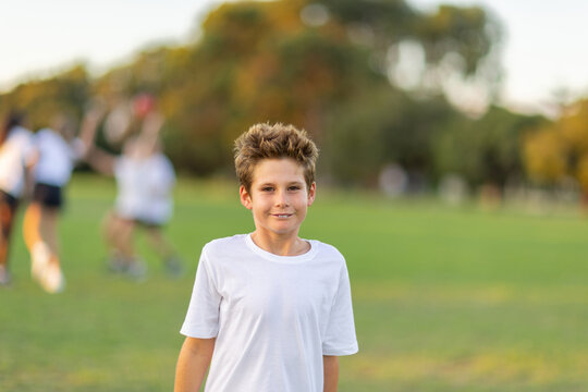 one young boy in white tee shirt with other kids out of focus playing in the background