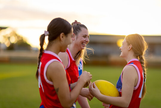 group of three young women in football uniforms upper body with golden light