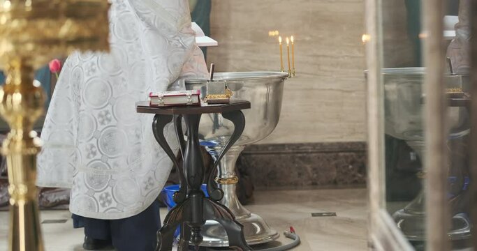 Priest dips sponge into bowl of holy water for rite of christening child. Christianity, faith, baptize