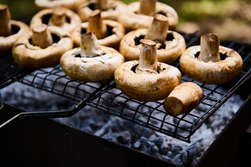 Selective focus raw marinated seasoned mushrooms champignons grilled on barbecue, vegetarian vegan summer food. Preparing delicious food in the open air. Summer picnic and chill out concept. Close-up