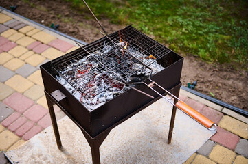 Top view empty grill grate over flaming charcoals on the barbeque grill in backyard, ready for...