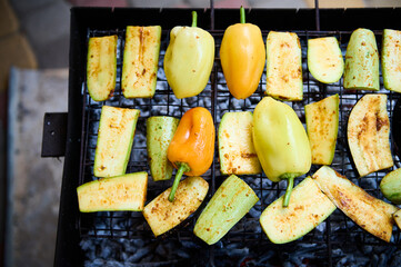 Food still life with marinated sliced zucchini and bell peppers grilling on the grate over charcoals. Barbeque. BBQ grill. Food background. Cooking. Healthy eating. Cookout. Picnic outdoor