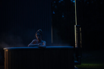 Fototapeta premium Woman relax in outside hot tub at night. Cinematic view