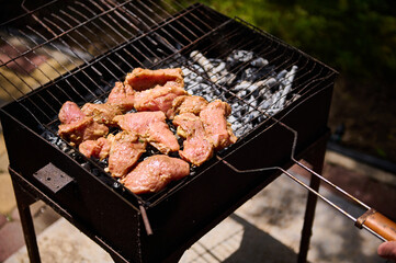 Overhead view of marinated pork tenderloin grilling on the grate over coals on barbeque grill outdoors. Food background. Food preparations. Selective focus