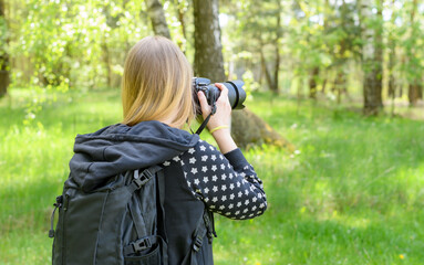 Dziewczyna z aparatem cyfrowym w lesie robiąca fotografie, ujęcie od tyłu