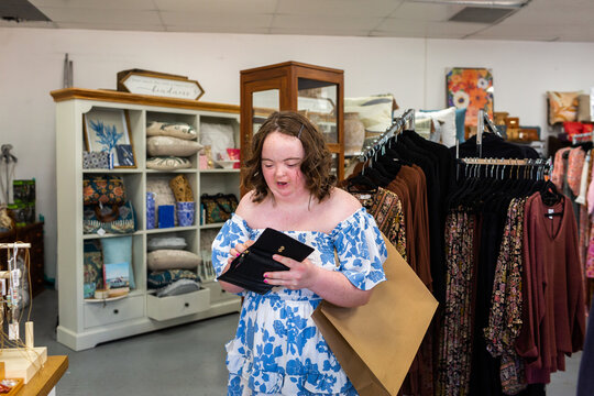 Young woman with a disability with her wallet out to make a purchase at shop