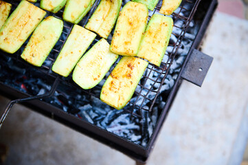 Selective focus raw slices of zucchini grilled on barbecue, vegetarian vegan summer food. Preparing delicious food in the open air. Summer picnic and chill out concept. Close-up. Barbeque Barbecue BBQ