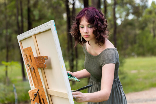 Young woman concentrating on painting on canvas