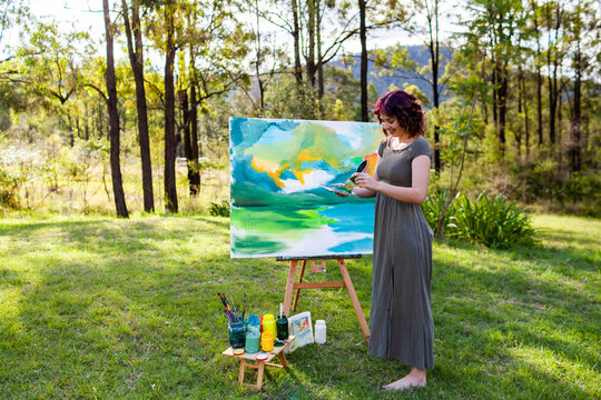 Young female artist mixing paint for artwork on canvas