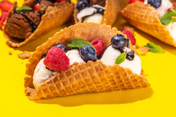 Various sweet taco ice creams. Waffle taco shells with chocolate and vanilla flavour ice cream with different fruits, berry, toppings