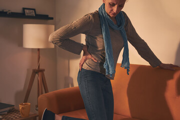 Woman with hip and back pain at home. - obrazy, fototapety, plakaty