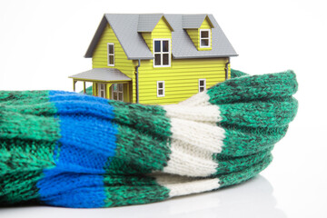 house model is insulated with a knitted scarf on a white background. the concept of keeping warm and cozy indoors at home. cold protection