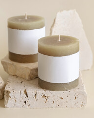 Candles with label on beige near cream travertine stones, Close up. Packaging mock up