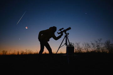 Astronomer looking at the starry skies, planets, meteor shower and lunar eclipse with a telescope.
