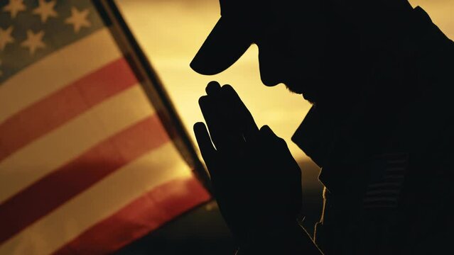 Silhouette of Military Praying for memorial day death in front of American flag