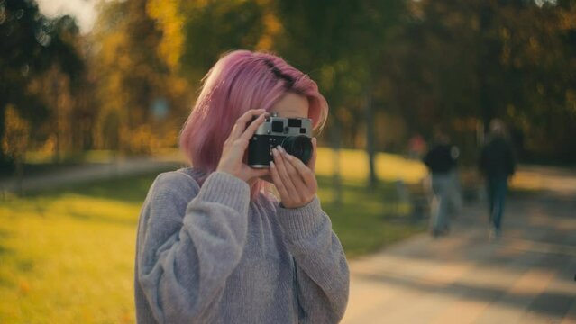 Young happy woman taking pictures on vintage camera, film photography hobby
