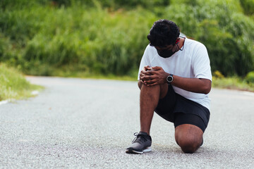 Close up Asian young sport runner black man wear watch sitting hands joint hold knee pain during...