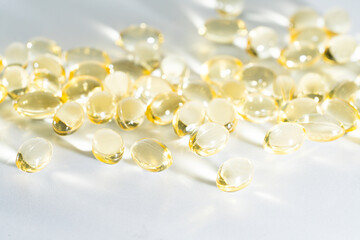 Vitamin D yellow supplement gel capsules, Fish Oil Omega 3 on white background, macro shot 