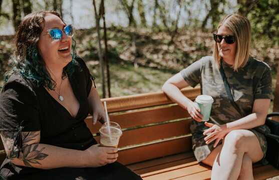 2 women sit on a bench talking and laughing
