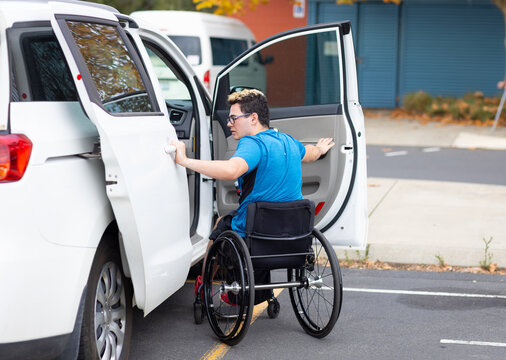 independent young person in wheelchair opening car doors to get into drivers seat