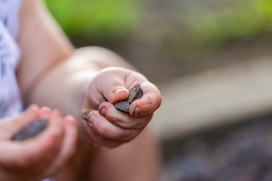 Baby holding small rocks in dirty hands outside