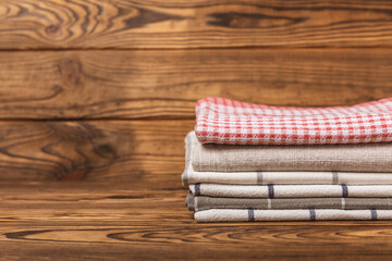 Checkered kitchen cotton towels folded on a brown texture table. Kitchenware. Kitchen towel or...