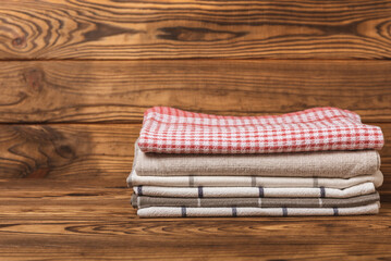 Checkered kitchen cotton towels folded on a brown texture table. Kitchenware. Kitchen towel or textile napkin. Copy space for text. Place for text. Tablecloth.
