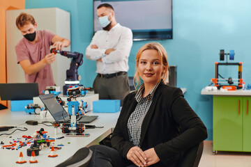 A woman sitting in a laboratory while her colleagues test a new robotic invention in the background