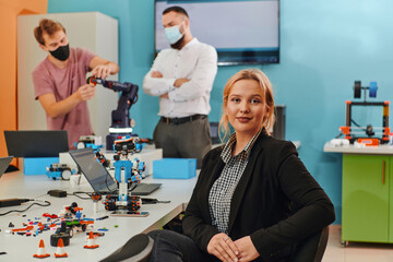 A woman sitting in a laboratory while her colleagues test a new robotic invention in the background