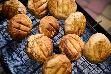 View from above of champignon mushrooms above flaming charcoal on barbecue grill. The picnic concept. BBQ Party. Grilled food background. The concept of barbeque, summer chill out, cookout and picnic