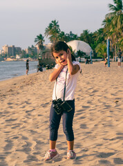 girl at the beach on a sunny afternoon using binoculars, walking and kicking the sand, Girl Looking at the beach through binoculars on a sunny afternoon, backlit, walking and smiling, kicking up the s