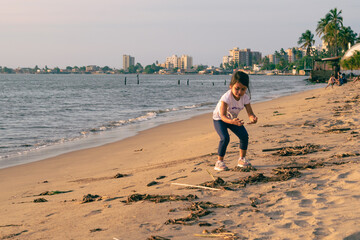 girl at the beach on a sunny afternoon using binoculars, walking and kicking the sand, Girl Looking at the beach through binoculars on a sunny afternoon, backlit, walking and smiling, kicking up the s