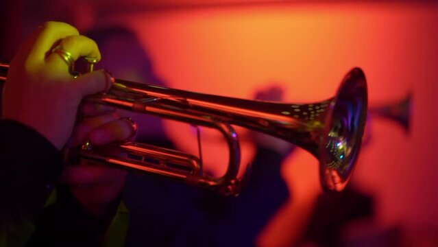 Musician playing musical trumpet wind instrument. Concert on stage, red light. Orchestra music.