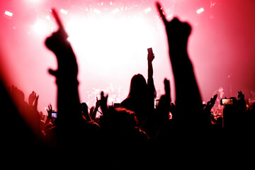 Fototapeta na wymiar Girl on shoulders silhouette. Happy people with raised hands at a music concert.