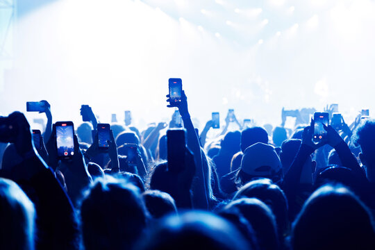 People at concert shooting video or photo using mobile phones.
