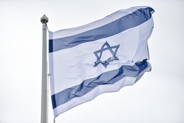 Israel state flag blown by the wind on a pole with clear sky on background