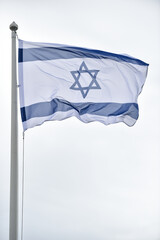 Israel state flag blown by the wind on a pole with clear sky on background