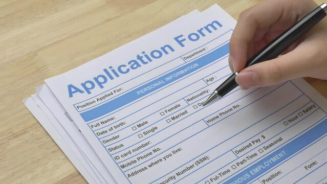Woman is holding a pen and pointing at an application form, checking the details before filling in her personal information. Job opportunity, human resources, recruitment and business concepts.