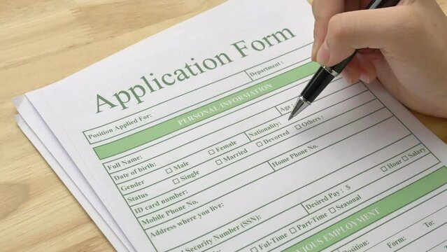 A woman holds a pen and points at an application form, checking the details before filling in her personal information. Concepts of hire jobs, work and career, human resources and business.