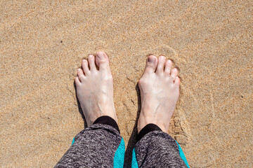 female feet with an increase in the joint of the big toe on the right foot, on the sand. Causes of the disease and treatment