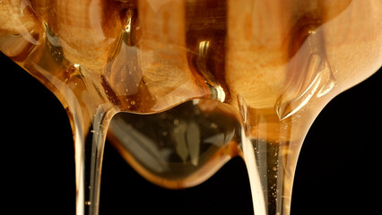 Thick organic honey dripping from a wooden honey spoon, close up © Евгений Логвиненко