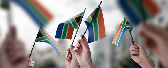 A group of people holding small flags of the South Africa in their hands